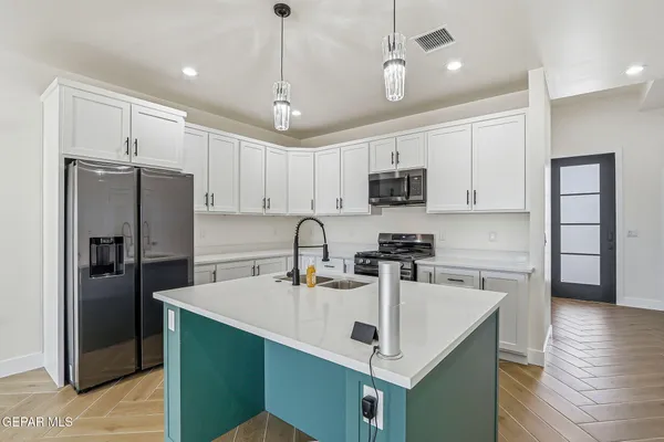 a kitchen with kitchen island a sink stainless steel appliances and refrigerator