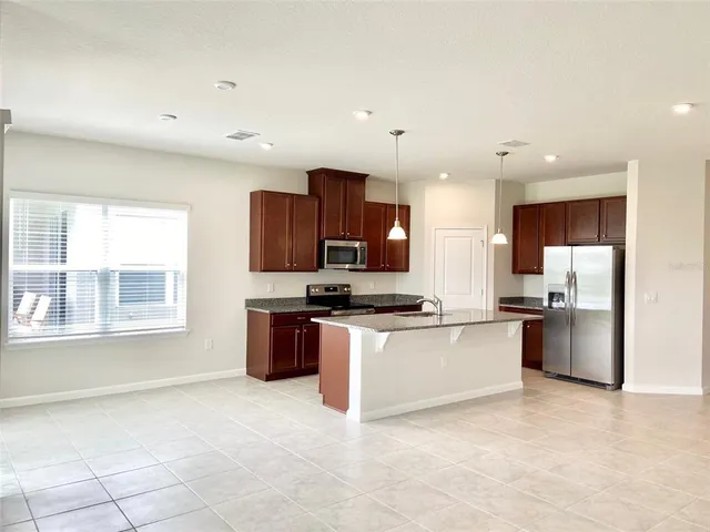 a kitchen with stainless steel appliances granite countertop a stove top oven a sink a refrigerator and white cabinets