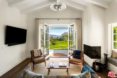 a living room with furniture a flat screen tv and a floor to ceiling window
