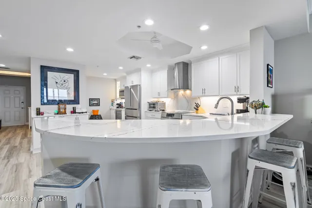 a kitchen with white cabinets a sink dishwasher and a stove with wooden floor