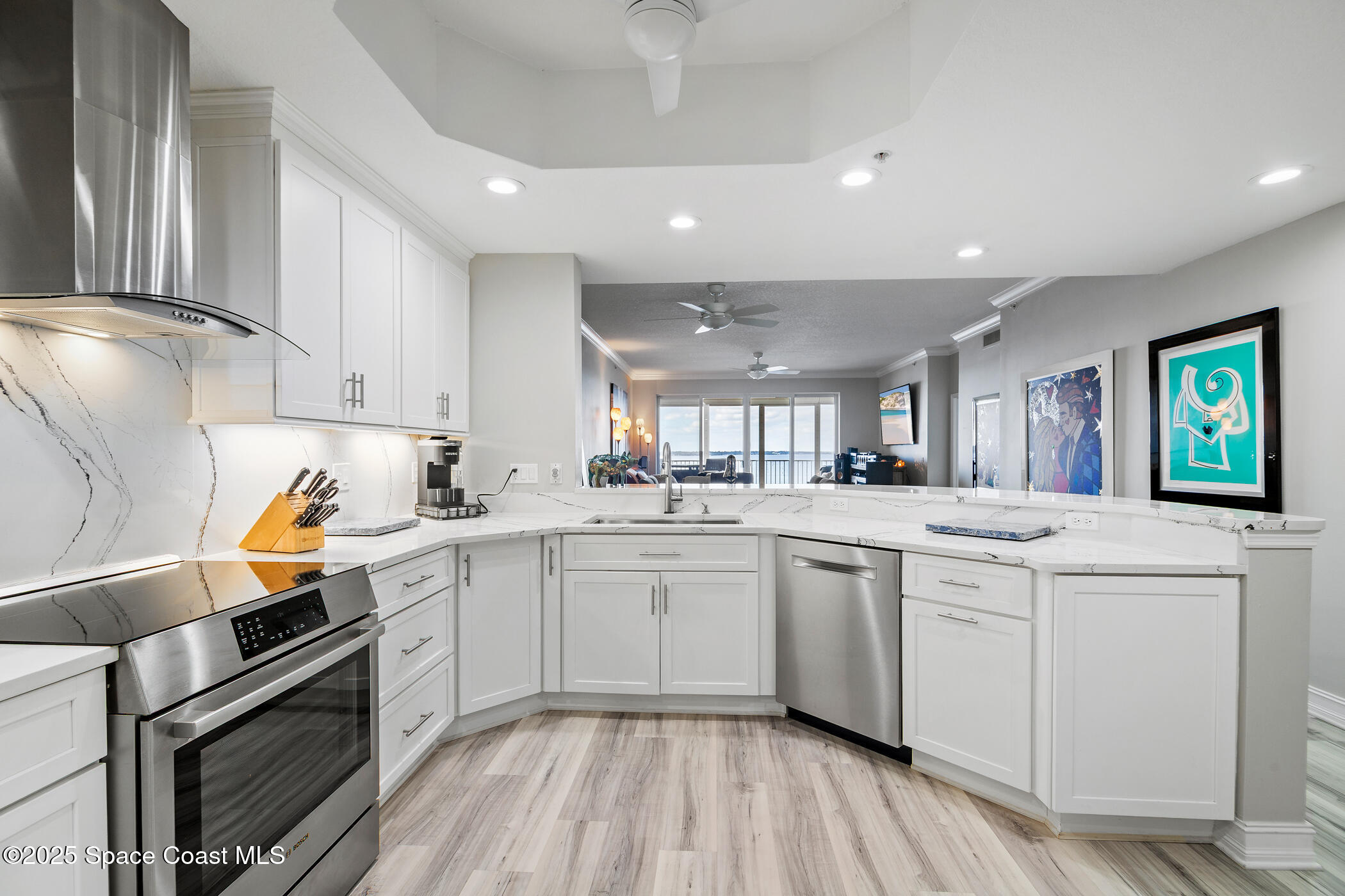 480 Sail Lane, Unit 703 Merritt Island, FL 32953 - Photo 9 of 41 a kitchen with white cabinets a sink dishwasher and a stove with wooden floor