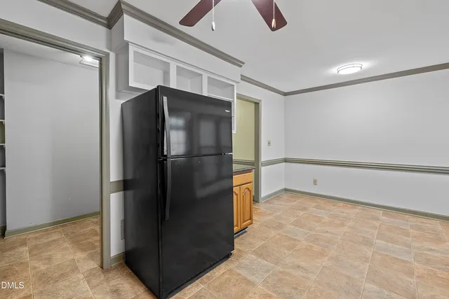 a view of a refrigerator in kitchen and an empty room