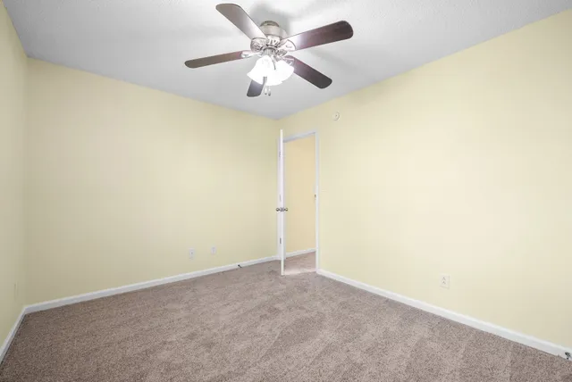 an empty room with a ceiling fan and a window