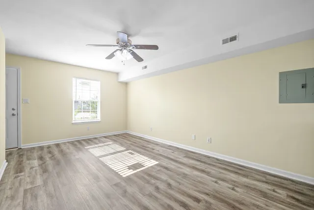 a view of empty room with wooden floor and fan
