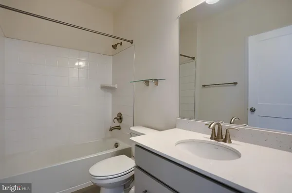 a bathroom with a granite countertop sink toilet a mirror and shower