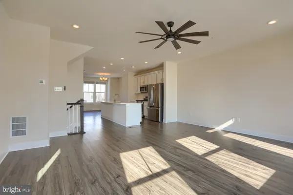 a living room with couches and kitchen view with wooden floor