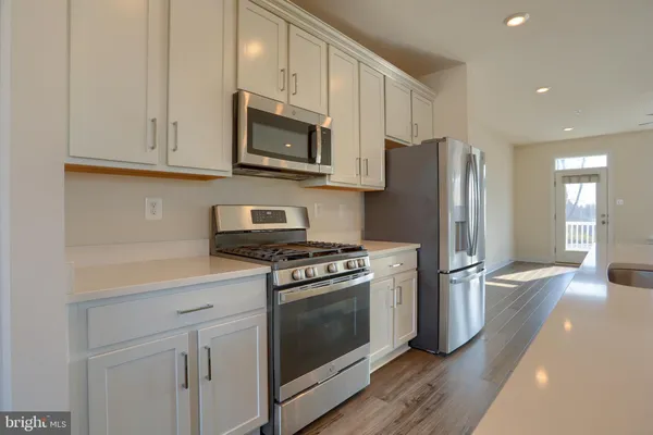 a kitchen with stainless steel appliances white cabinets a stove a sink and a refrigerator