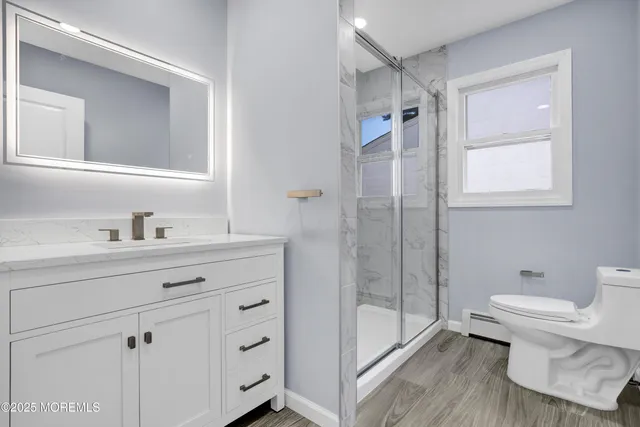 a bathroom with a granite countertop sink toilet a mirror and shower