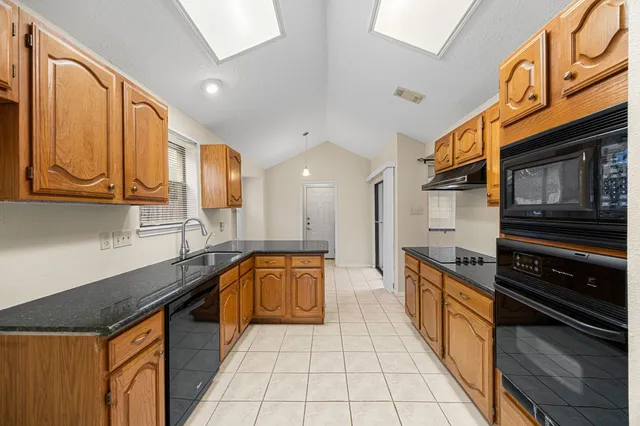 a large kitchen with stainless steel appliances granite countertop a sink and cabinets
