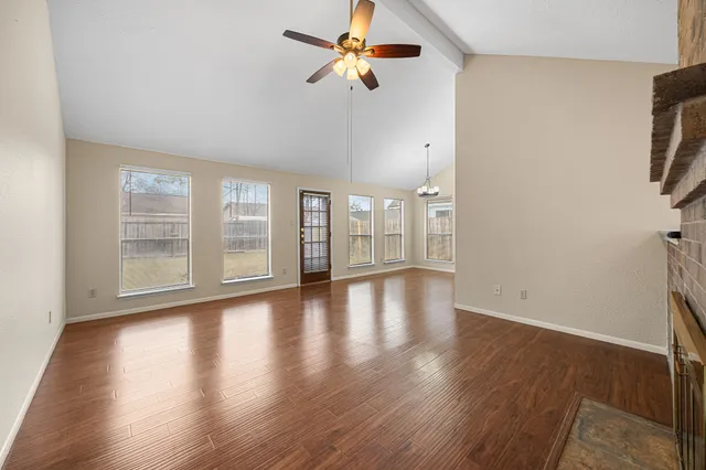 a view of an empty room with window and wooden floor