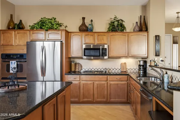 a kitchen with stainless steel appliances granite countertop a refrigerator a stove and a sink with wooden floor