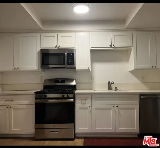 a kitchen with white cabinets and black appliances