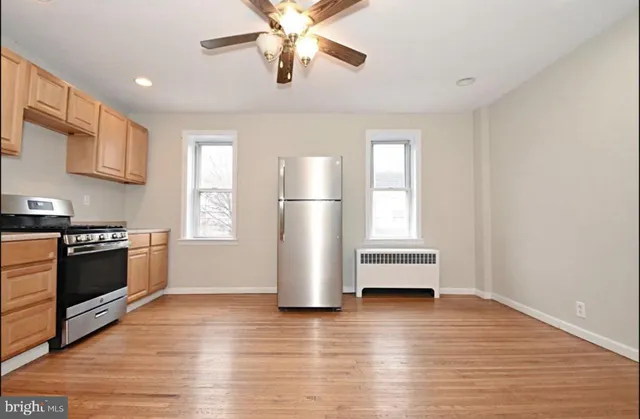 a kitchen with stainless steel appliances wooden floor and a refrigerator