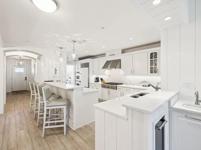 a kitchen with a sink a stove a refrigerator and white cabinets with wooden floor