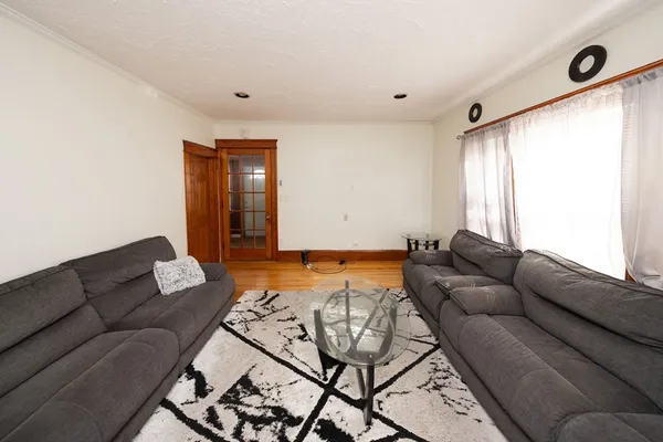 a view of an empty room with wooden floor and a ceiling fan
