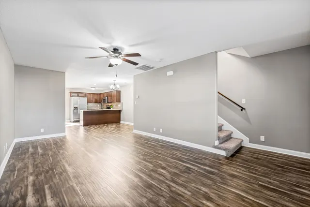 a view of empty room with wooden floor and kitchen view