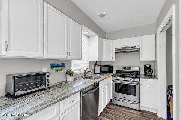 a kitchen with granite countertop a sink a window and cabinets