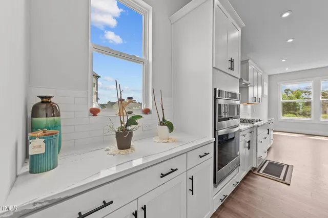 a kitchen with stainless steel appliances granite countertop a sink a stove and a wooden floors