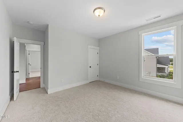 a bed sitting in a spacious bedroom next to a window