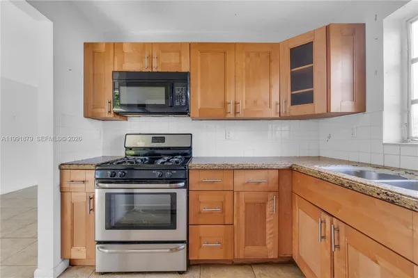 a kitchen with granite countertop stove top oven microwave and cabinets