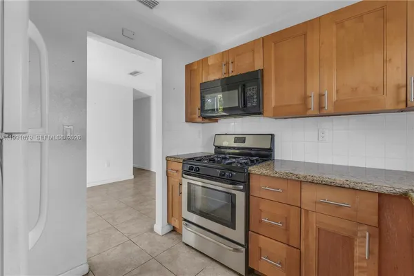 a kitchen with stainless steel appliances granite countertop white cabinets and a stove top oven