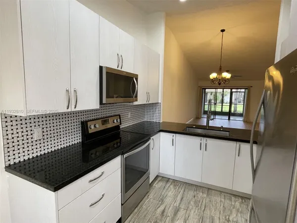 a kitchen with granite countertop a stove a sink and a microwave
