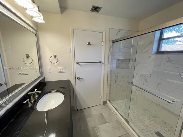 a bathroom with a granite countertop sink a mirror and shower