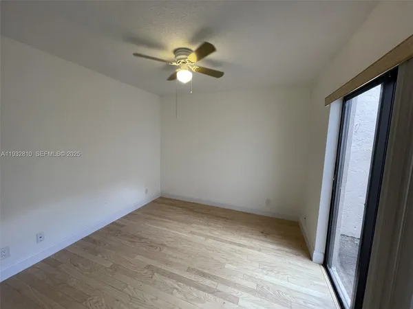 an empty room with windows and fan