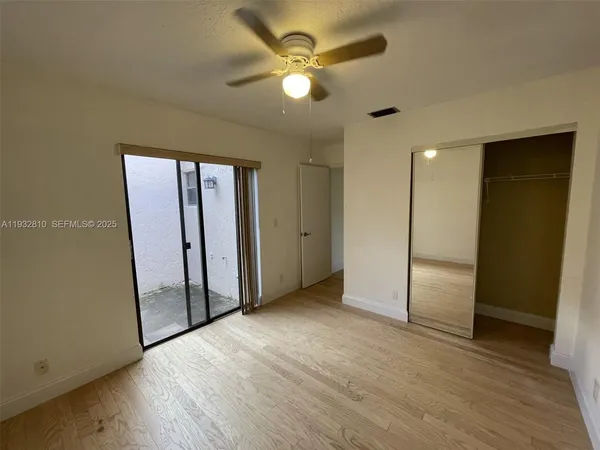 an empty room with wooden floor and a ceiling fan