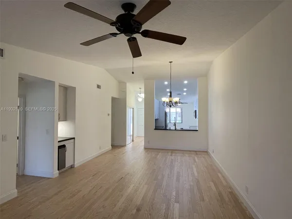 a view of a kitchen with a refrigerator wooden floor and a ceiling fan
