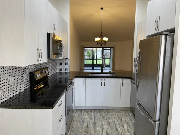a kitchen with stainless steel appliances a refrigerator a sink a stove a microwave and island