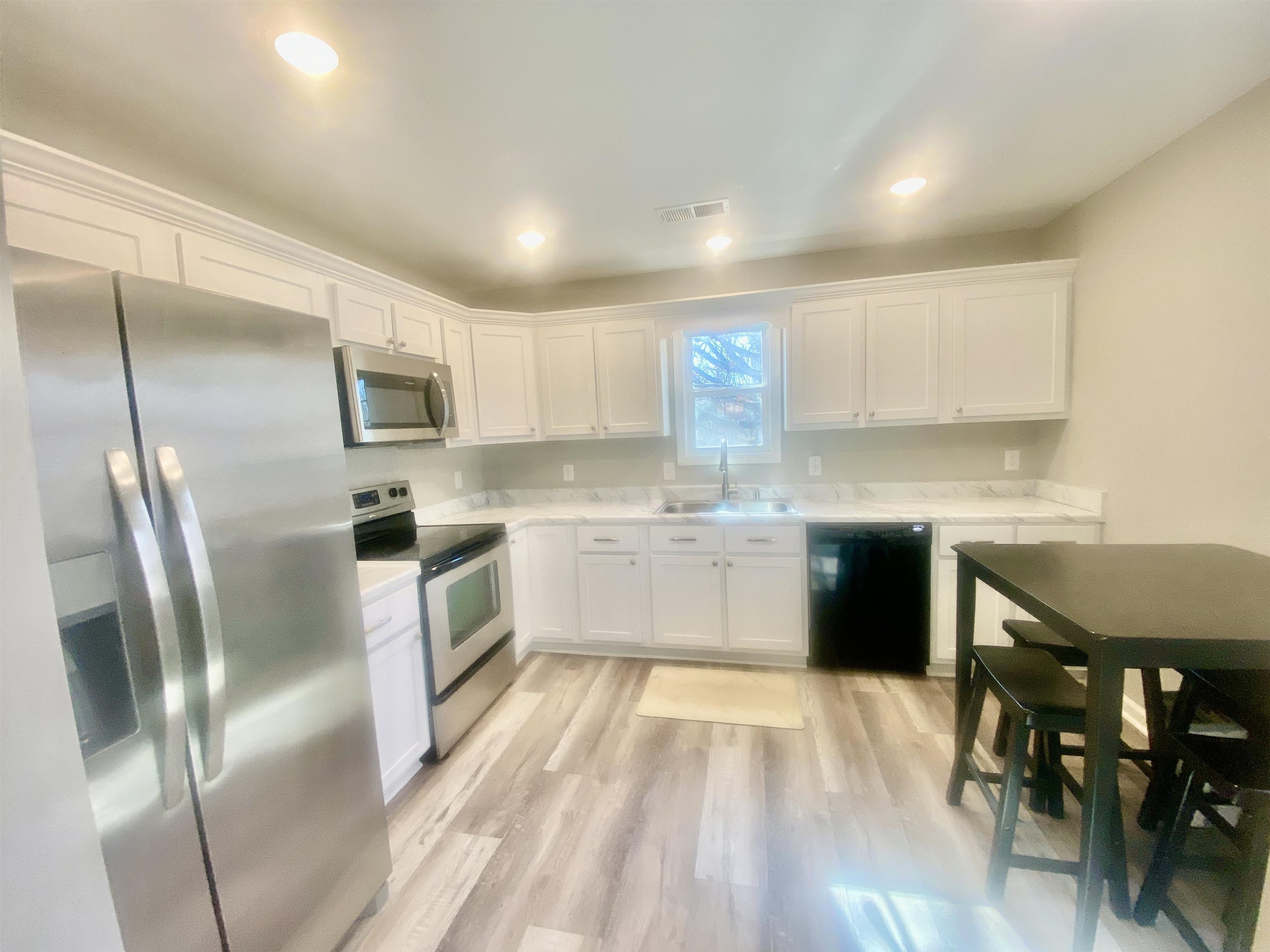 465 Post Office Road Michie, TN 38357 - Photo 10 of 11 Kitchen with stainless steel appliances, white cabinets, sink, and light laminate style flooring
