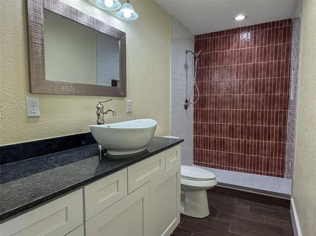 a bathroom with a granite countertop sink a toilet and mirror