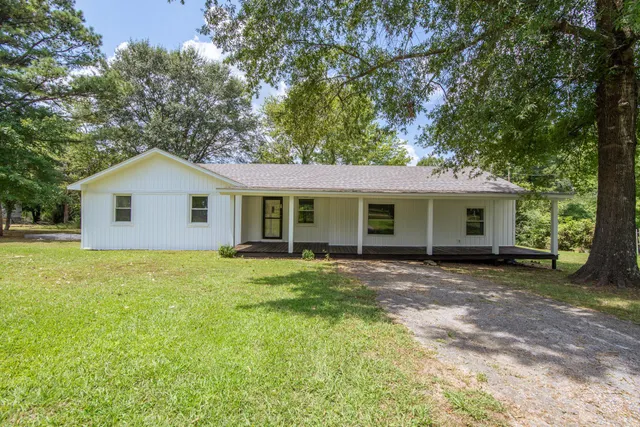 a view of a house with a yard and large tree