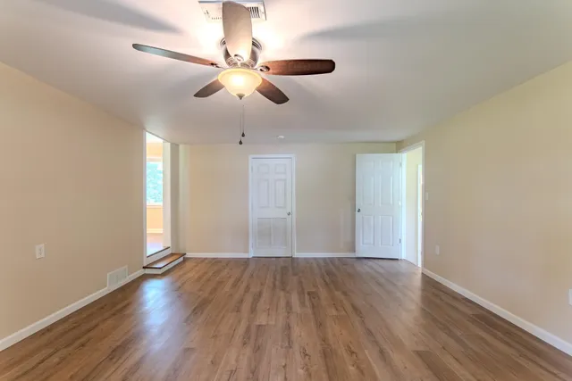 a view of an empty room with wooden floor and a window