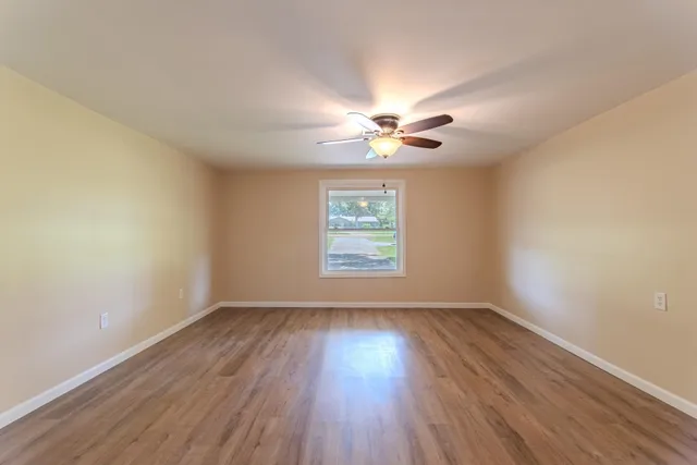 a view of an empty room with wooden floor and a window