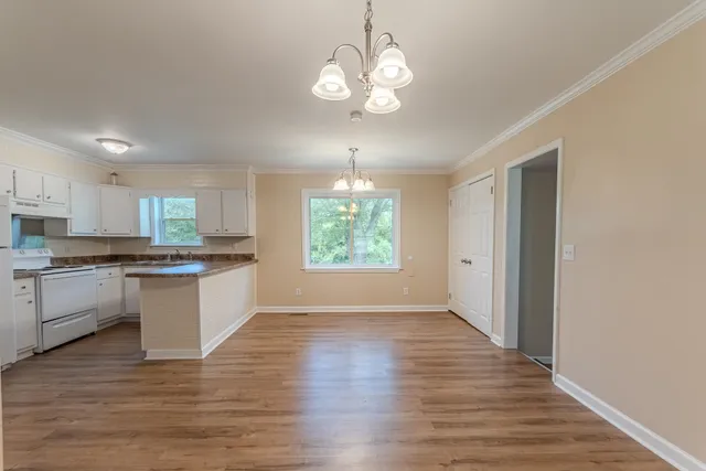 a kitchen with stainless steel appliances granite countertop a stove top oven a sink dishwasher and a refrigerator with wooden floor