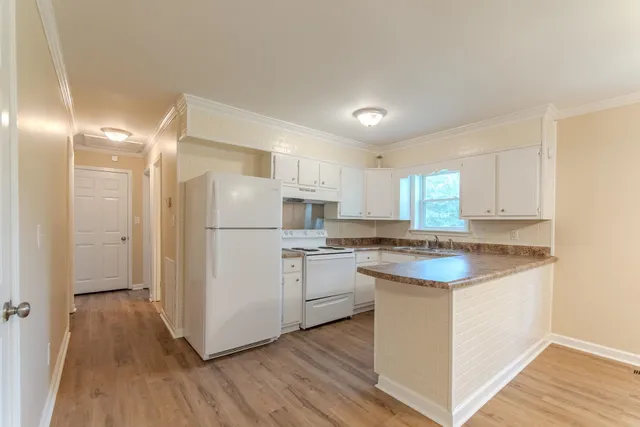 a kitchen with a refrigerator a sink and wooden floor
