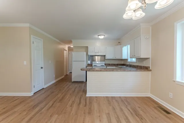a room with kitchen island granite countertop wooden floors and white cabinets