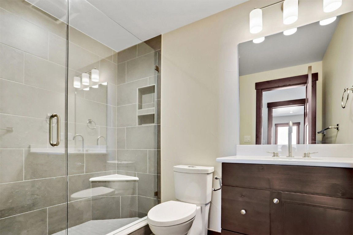 62 Vendette Road Silverthorne, CO 80498 - Photo 23 of 35 a bathroom with a toilet a sink a glass door a shower a mirror and vanity
