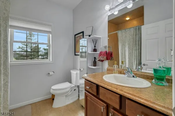 a bathroom with a granite countertop sink a toilet and a mirror