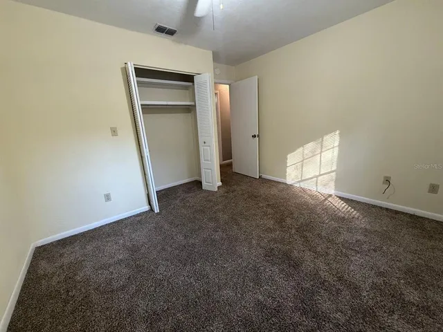 an empty room with a ceiling fan and window