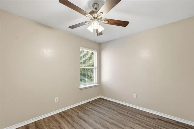 an empty room with windows and chandelier fan