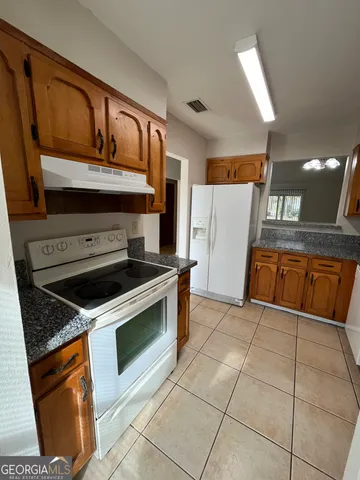 a kitchen with granite countertop a stove top oven and cabinets