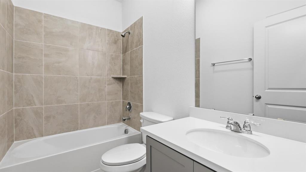 2529 Rivers W Road Anna, TX 75409 - Photo 12 of 40 Bathroom featuring a built-in tub with tile surround, a built-in shower niche, a single vanity with an integrated sink, a light-toned countertop, and a mirrored wall