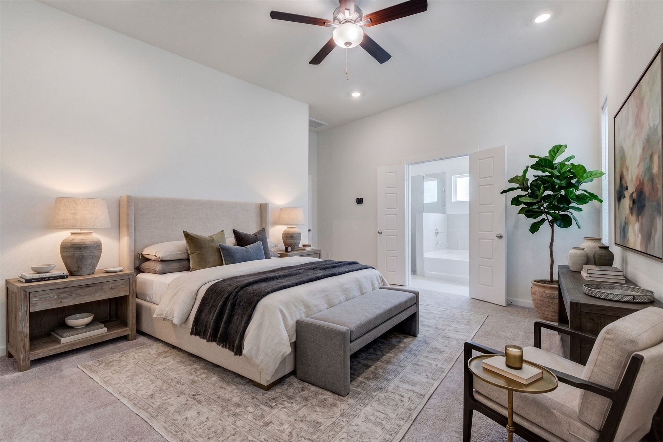 6467 Escondido Drive Rosharon, TX 77583 - Photo 5 of 32 Primary bedroom view showcasing the private en-suite bath entry, plush carpet, high ceiling, ceiling fan, and recessed lighting. The room feels open and serene, with a flexible wall layout for furniture placement and direct access to the bathroom for added everyday convenience. This photo has been virtually staged for visual reference.