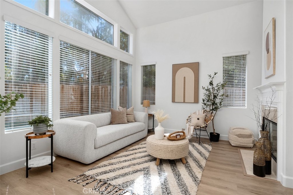 56 Acorn Ridge Rancho Santa Margarita, CA 92688 - Photo 12 of 57 Living Room: Soaring ceilings and a wall of windows fill the room with natural light, while the fireplace and wood-look flooring add warmth and visual interest.