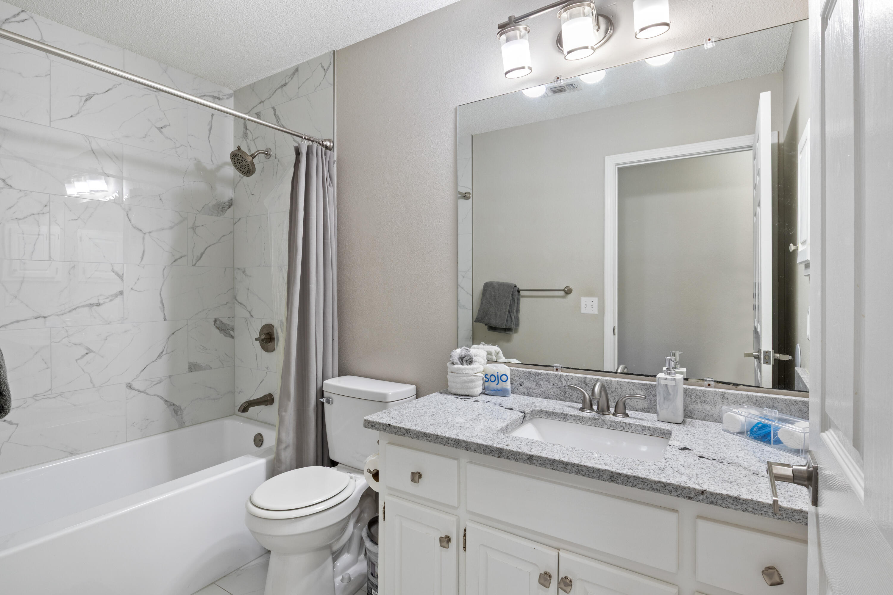 2005 Cardinal Lane Navarre, FL 32566 - Photo 24 of 37 a bathroom with a granite countertop sink a toilet a mirror a bathtub and shower