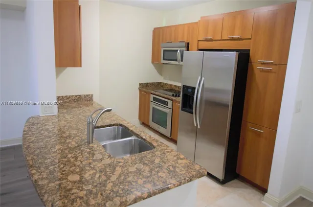 a kitchen with stainless steel appliances granite countertop a refrigerator a stove and a sink