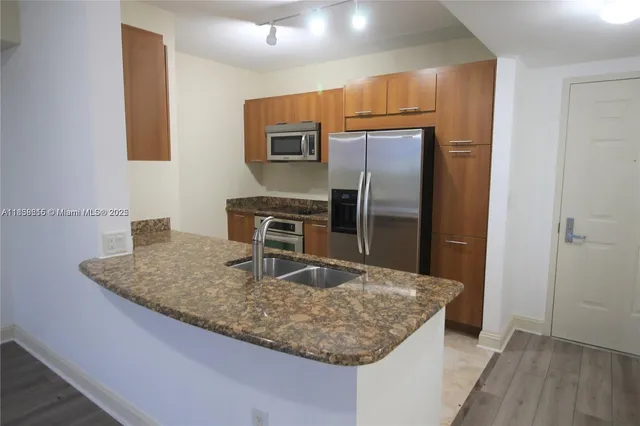 a kitchen with kitchen island a counter top space cabinets and stainless steel appliances